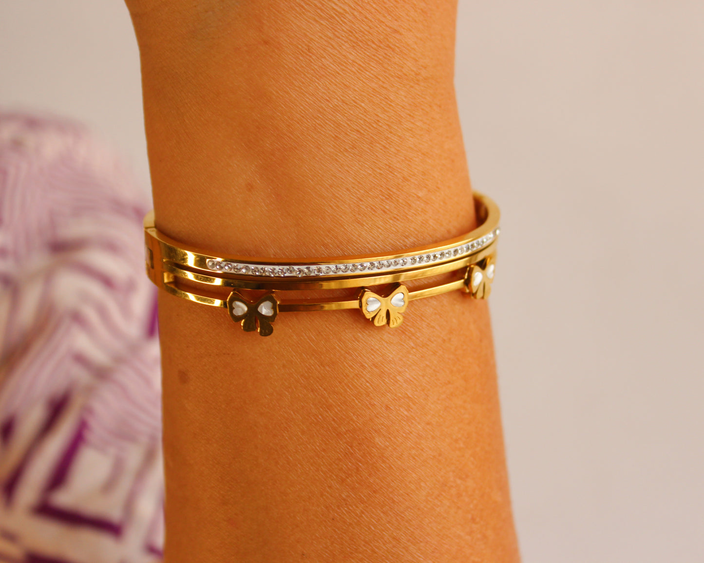 Gold bracelet with diamond accents on a wrist against a neutral background