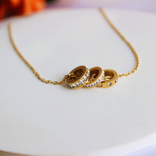 Gold necklace with three interlocking rings on a white plate